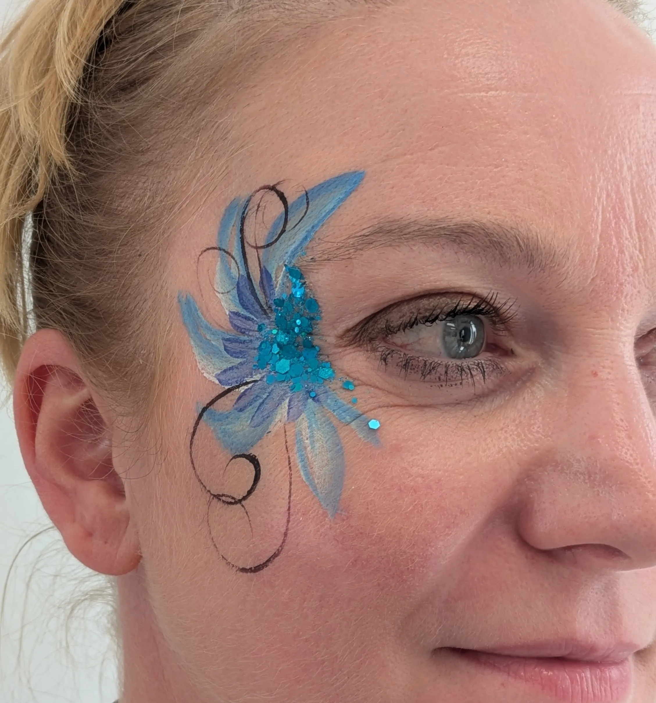 Maquillage artistique bleu floral avec paillettes turquoise autour de l&rsquo;&oelig;il